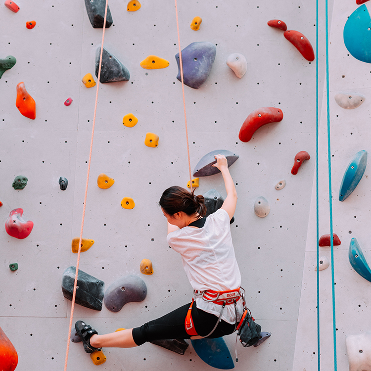 A woman climbs a rock-climbing wall