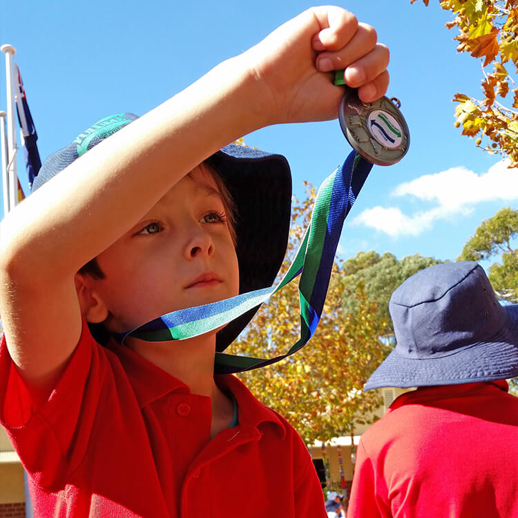 Dartanyon in school uniform holding his medal