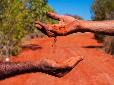 aboriginal Australians holding red dirt